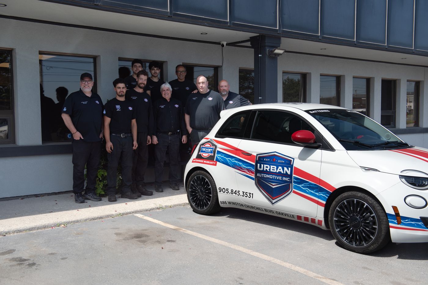 The Urban Automotive team with their branded car outside the Oakville shop